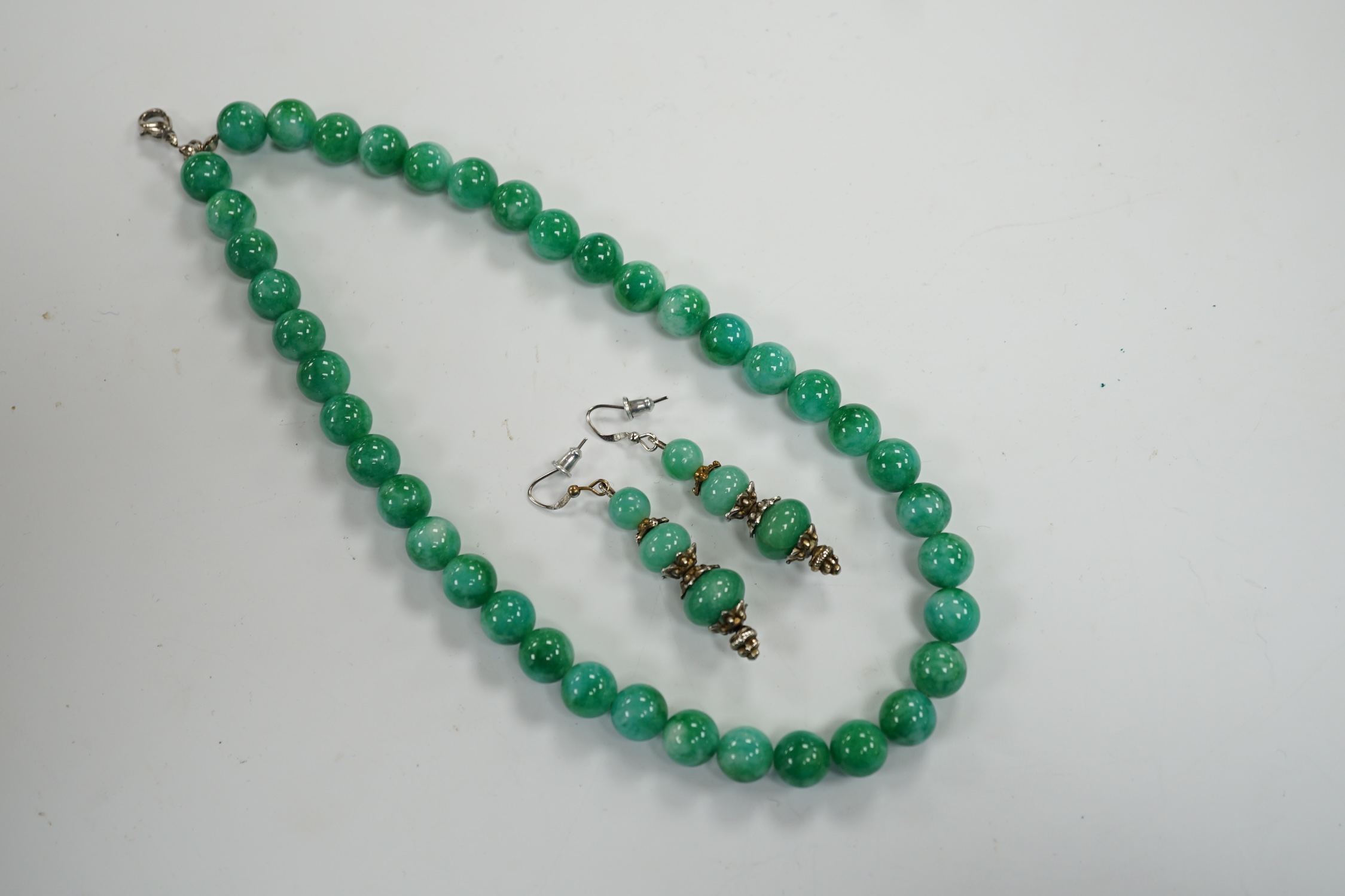 A single strand jadeite bead necklace, 41cm and a pair of jadeite earrings, stamped 18k.